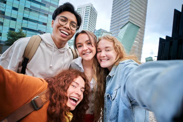 Erasmus Avrupa 'da selfie çeken çok ırklı gülümseyen üniversite öğrencileri. Üniversite kampüsünün dışında gülümseyen mutlu arkadaşlar fotoğrafı. Neşeli genç sınıf arkadaşları poz verir ve eğlenir..