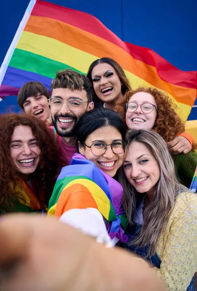 LGBT gençlerinin dikey selfie 'si gey gurur gününü gökkuşağı bayrağını bir arada tutarak kutluyor. Homoseksüel toplum gülümsüyor ve neşeli bir oto portre çekiyor. Lezbiyen çift arkadaş nesli z.