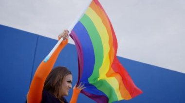 Genç, neşeli Latin travesti eşcinsel geçit töreninde gökkuşağı bayrağı sallıyor. Transseksüel insanlar LGBT özgür aşk festivalini kutluyor. 