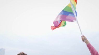 Mavi gökyüzünde rüzgarda sallanan LGBT gökkuşağı. El ele tutuşan gay gurur bayrağı. Lezbiyen, gey, biseksüel, homoseksüel, transseksüel sosyal hareketler. Mutluluk kavramı özgürlük, aynı cinsiyetten çifti sevmektir.. 