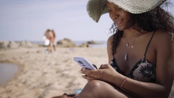 Joyeux Jeune Fille Latine Assis Sur Plage Tapant Sur Téléphone — Video