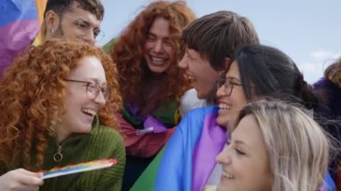 Neşeli, sırıtan bir grup genç arkadaş eşcinseller gününü kutluyorlar. LGBT topluluğundan mutlu insanlar dışarıda eğleniyor. Lezbiyen, homoseksüel, transseksüel ve ikili olmayan insanlar..