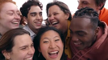 Çok ırklı bir grup, dışarıda selfie çeken kız ve erkek öğrenciler gülümsüyor. Çok kültürlü gençlerin birlikte eğlendiği mutlu bir hayat tarzı olan arkadaşlık kavramı. Yedi meslektaşım hafta sonunun tadını çıkarıyor