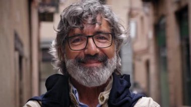 Yaşlı gri saçlı adam mutlu bir şekilde gülümsüyor. Şehir caddesinde kameraya bakıyor. Grizzled Olgun beyefendi video için neşeli ve kendinden emin poz veriyor. Emekli insanlar ve kopyalama alanı.
