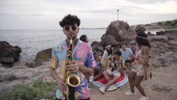 Strzał Młodego Saksofonisty Bawiącego Się Grupą Przyjaciół Bawiących Się Tle — Wideo stockowe