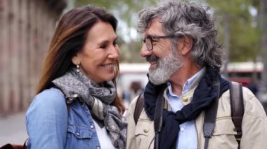 Şehirde video için poz veren mutlu yaşlı turist çifti. Birlikte seyahat eden gülümseyen son sınıf öğrencileri. Erkek ve kadın birlikte kameraya bakıyor. Sevgiyle hafta sonu kaçamağının tadını çıkarıyorlar.