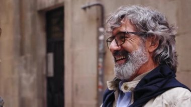 Açık havada olgun bir kadını kucaklayan yaşlı, gri saçlı adamın videosunu kapat. Arka planda yaşayan evli çiftler arasında aşk kucaklaşması. Emeklilik ortağının sevecen ilişkisi.