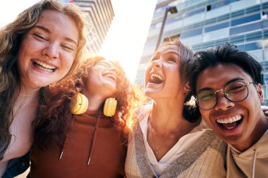 Çok ırklı genç üniversite öğrencilerinin gülen selfie 'si. Dört arkadaş kampüste gülümseyip şakalaşıyor. Neşeli sınıf arkadaşları heyecanlı bir şekilde dışarıda eğleniyorlar.. 