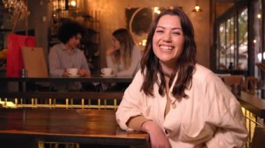 Kafeterya masasına yaslanan neşeli kızın uzay videosunu kopyala. Güçlü Latin kadın gülümseyen kameraya bakarak poz veriyor. Genç insanlar içeride eğleniyor. Alışveriş sonrası üç iş arkadaşı buluşması.