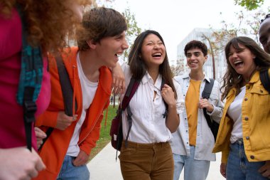 Diverse group of smiling young students gathered outside college campus. Happy classmates and friends enjoying the break between classes. Generation z people laughing outdoors together on spring day. clipart