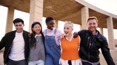Çok ırklı bir grup öğrenci kameraya sarılıp yürüyorlar. Gün batımında okulun dışında gülüyorlar. Birlikte eğlenen genç insanlar topluluğu. Sosyal toplanma ve gençlik kültürü