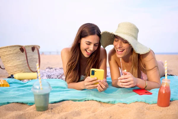 Para Młodych Pięknych Dziewczyn Patrzących Uśmiechnięty Telefon Leżący Plaży Dwie — Zdjęcie stockowe