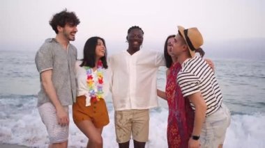 Deniz kıyısında gülen beş genç çok kültürlü arkadaşın portresi. Sahilde dolaşan çok ırklı genç kadınlar ve erkekler. Yüksek kalite 4k görüntü
