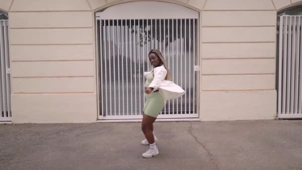 年轻的黑人妇女在户外跳舞 她有时髦的发型和衣服 她有节奏地移动 优质Fullhd影片 — 图库视频影像