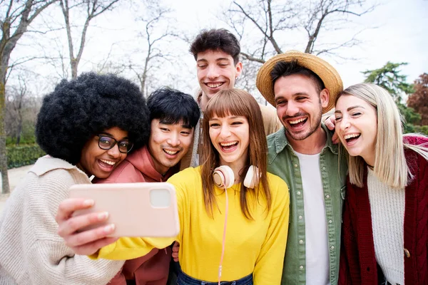 多人種の学生のグループと彼らは電話を見ている間に多くの笑い デバイス内のチェックマルチメディアながら 彼らは幸せでフレンドリーな外観 — ストック写真