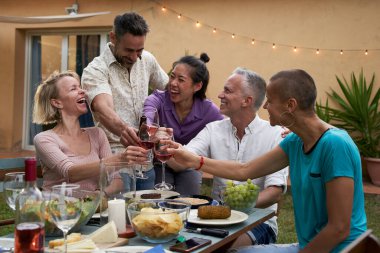 Orta yaşlı insanlar yazın bardaklarını şarapla tokuştururlar. Arkadaşlar dışarıda eğleniyor. Yüksek kalite fotoğraf