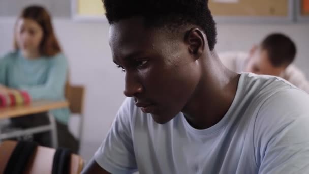 年轻的非洲裔美国学生在课堂上拿着手写的课堂笔记 黑人在多种族学校上课 年轻的男孩和女孩坐在书桌前 教育的概念 — 图库视频影像