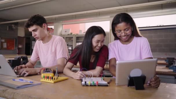 一个由三名来自技术高中的年轻学生组成的小组做一个技术团队项目 使用计算机咨询的人对他们在电子技术课上的做法表示怀疑 — 图库视频影像