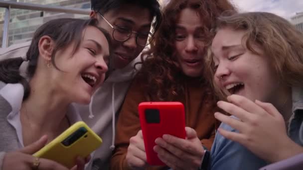 一群多种族同学看着他们的智能手机分享社交媒体 白天在大学外面愉快地聚在一起 朋友之间用手机可以产生乐趣 — 图库视频影像