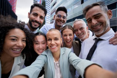 Telefonla fotoğraf çeken mutlu iş adamlarının selfie 'si. Çok ırklı takım çalışması büyük bir grup meslektaşın portresini çekiyor. Bir finans merkezinde çeşitli ofis çalışanlarının kurumsal yaşam tarzı