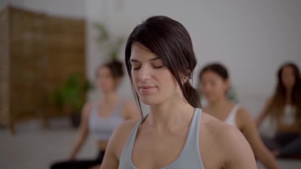 闭目养神的年轻成年女性在室内练习瑜伽 集中在课堂上冥想的女孩 社区的健康生活方式 女性健康和每天早上的例行公事 — 图库视频影像