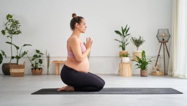 Yandan bakınca, yoga yapan ve sınıfta meditasyon yapan hamile beyaz bir kadının portresi görülüyor. Kadın fitness ve gelecekteki annelik. Sağlık, farkındalık, rahatlama ve sağlık kavramı. 