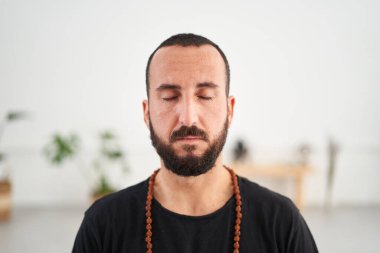 Sakallı beyaz adam yoga meditasyonu yapıyor. Orta yaşlı erkek, gözleri kapalı evde Mudra gösterisi yapıyor. Erkeksi sağlık, vücut bakımı ve akıl sağlığı kavramı.