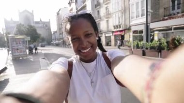 Genç siyahi, gülümseyen, nüfuzlu kız sosyal medya için sokakta telefonla kayıt yapıyor. Afro-Amerikalı mutlu turist kadın takipçileri için selfie hücresini kullanıyor. Z jenerasyonu ve gezici video açık havada.