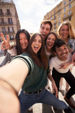 Genç, çok ırklı ve güzel arkadaşların dikey selfie 'si dışarıda birlikte eğleniyorlar. Mutlu kameraya bakan heyecanlı insanlar güneşli bir günde şehri gezmekten zevk alıyorlar. Z nesli ve tatiller