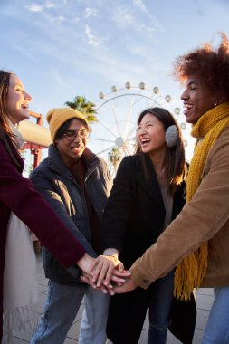 Dikey grup, lunaparkta el ele tutuşan çok ırklı insanlara gülümsüyor. Mutlu Nesiller genç arkadaşlar bir araya geliyor. Açık hava tatil zamanı güneşli kış tatilleri. Dostluğumuzu kutluyoruz.