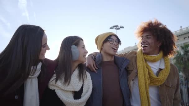 笑う人々の多種多様なグループは抱擁し 楽しんでいます 笑顔の若い友人が休日を楽しんで歩いています 陽気な冬の日に屋外を散策する国際エラスムスの学生の陽気な同僚 — ストック動画