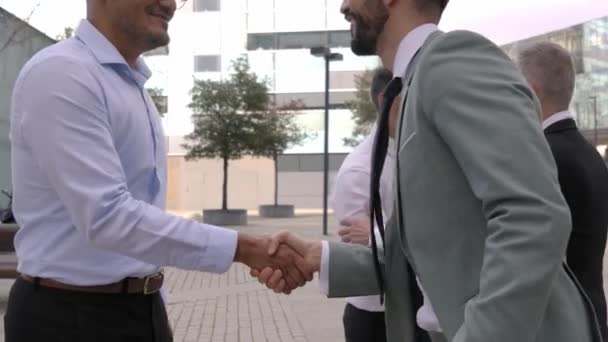 多様な笑顔のビジネスマンが屋外に立っている自信を持って互いに挨拶します 外部のオフィスビルを提示する正式な服装の異なる幹部 プロの人がシェイクハンドに合う — ストック動画