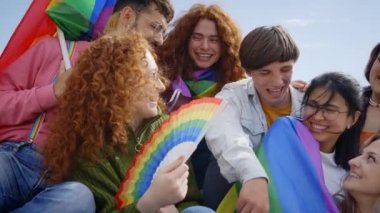 Çok ırklı gruptaki heyecanlı insanlar, eşcinsel onur gününü sokakta kutlamak için toplandılar. Çeşitli neşeli arkadaşlar LGBT partisinde gökkuşağı bayraklarıyla birlikte eğleniyorlar. Z jenerasyonu ve cinsel özgürlük.