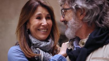 Dışarıda sevgi dolu davranan mutlu, olgun bir çifti yakından takip edin. Gülümseyen yetişkin bir çift birlikte vakit geçirip kucaklaşıyorlar. Aşık romantik insanlar ve emeklilikte pozitif ilişkiler.. 