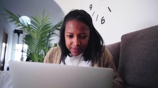 Χαμογελώντας Νεαρή Μαύρη Γυναίκα Χρησιμοποιώντας Φορητό Υπολογιστή Κάθεται Στον Καναπέ — Αρχείο Βίντεο