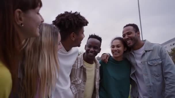 快乐的年轻人团体多种族的朋友拥抱在外面享受春天的日子 笑着的学生们站在公园里笑着聚在一起聊天 两代人之间的积极关系 — 图库视频影像