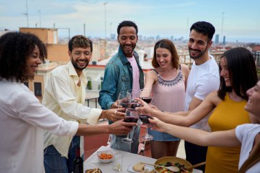 Çok uluslu gülümseyen genç insanlar kadehlerini kaldırarak çatıda doğum günlerini kutluyorlar. Arkadaşlar terasta öğle yemeğinde alkollü içecekler içiyorlar. Milenyum, yaz tatilinin tadını çıkarıyor.