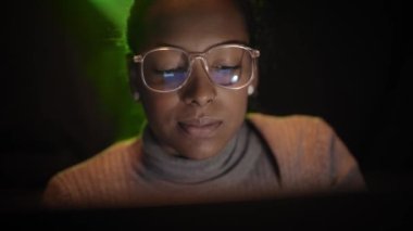 Genç bir Latin iş kadını bilgisayar başında geç saatlere kadar çalışıyor. Dizüstü bilgisayar ekranı gülümseyen kız gözlüklerine yansıyor. Geceleri gururlu bir kadın işçi. Projelerini dijital cihaza odaklayan insanlar