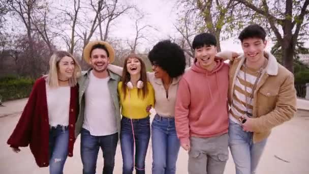 公園で一緒に散歩する大規模なグループの笑顔の若者 カジュアルな多種多様な人々が抱擁し 屋外で秋の日に楽しんでいます コミュニティの友情と社会関係の概念 — ストック動画