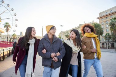 Çok ırklı arkadaşlar lunaparkta geziniyor kış haftasonu kucaklaşıyorlar. Grup gülen iş arkadaşları buluşup birlikte takılıyorlar. Nesiller boyunca insanlar dışarıda gülümseyerek yürüdüler.. 