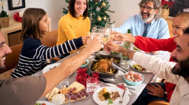 Gülen ailenin Noel yemeğini kutlaması masada şarapla kadeh kaldırması şerefine. Mutlu insanlar tatil toplantılarında eğleniyor. Farklı nesiller Aralık ayının keyfini çıkarıyorlar.. 