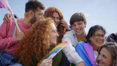 Grup gülen insanlar LGBT haklarını göstermek için dışarıda toplandı. Gökkuşağı bayrakları ve hayranlarıyla birlikte eğlenen mutlu arkadaşlar. Z jenerasyonu ve cinsel özgürlük.
