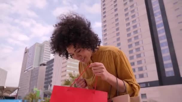 视频中 令人惊讶的年轻的非洲裔美国女性购物狂拿着纸袋购物 看着站在商场外跳舞的相机 人们在黑色星期五很兴奋 销售季节 — 图库视频影像