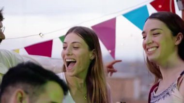 Heyecanlı, neşeli grup arkadaşları çatıdaki partide bira şişesi tutuyorlar. Neşeli gençlerin bir araya gelmesi yaz günü dışarıda eğlenmesi mutlu doğum günlerini coşkuyla dans etmesi.. 