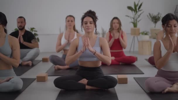 女教师和小组年轻人在室内练习瑜伽 集中在课堂上冥想的人 社区的健康生活方式 健康和日常活动 — 图库视频影像