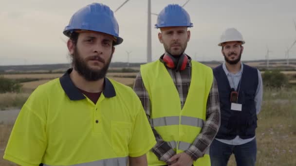Zbliżenie Inżynierów Pracy Zespołowej Poważnie Patrzących Kamerę Elektrowni Wiatrowej Wsi — Wideo stockowe