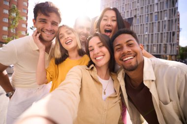 Dışarıda gülümseyen çok kültürlü genç arkadaşlar selfie grubu. Neşeli insanlar mutlu poz veriyor. Gezici fotoğraflara sarılıyorlar. Hep birlikte kameraya bakıyoruz. Z kuşağındaki toplulukta olumlu ilişkiler