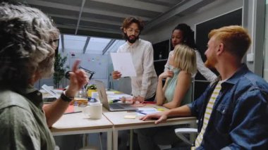 Çok ırklı bir çalışma ekibinin yeni profesyonel başarıya coşkuyla tepki vermesi genç ve olgun meslektaşlarının gülen bir ifadeyle toplanması. Bir grup ofis çalışanı kutlama yapıyor.