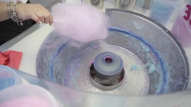 Tatil festivali sırasında pembe pamuk şeker yapan bir kadın. Lunapark fuarında makine ve insan elini kapatın. Pamuk helva yapmak için bir cihaz. İnsanlar dışarıda..
