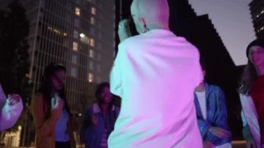 Harekete geçin. Şık insanlar şehrin arka planında, neon ışıklı dans salonunda hip-hop yapıyor. Gençlik kültürü, hareket, tarz ve moda, aksiyon. Modaya uygun bir portre. Yüksek kalite